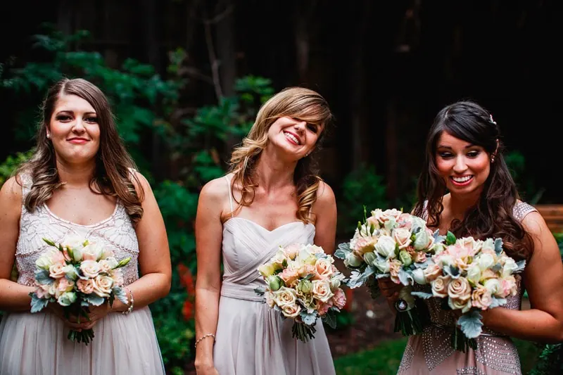 Three bridesmaids holding blush rose posies
