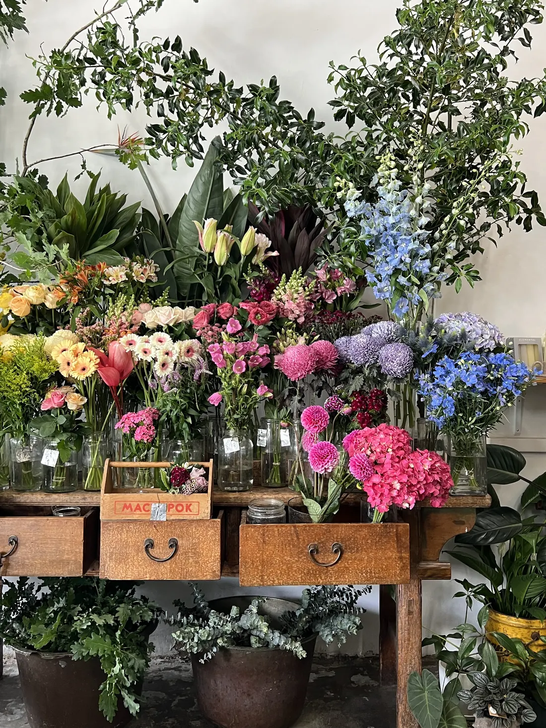 Buckets of flowers on vintage timber drawers inside Casa Verde