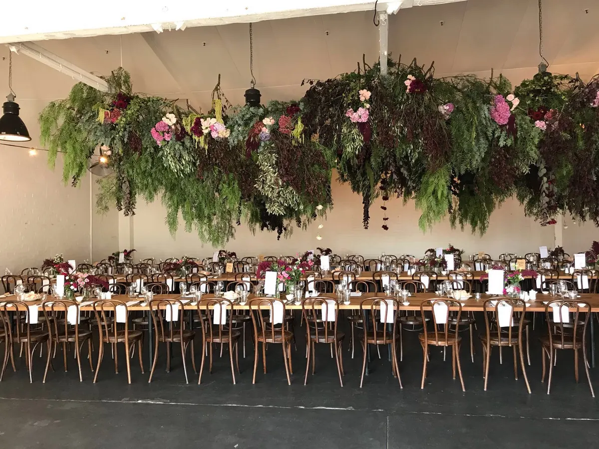Floral ceiling installation hanging over long tables set for an event