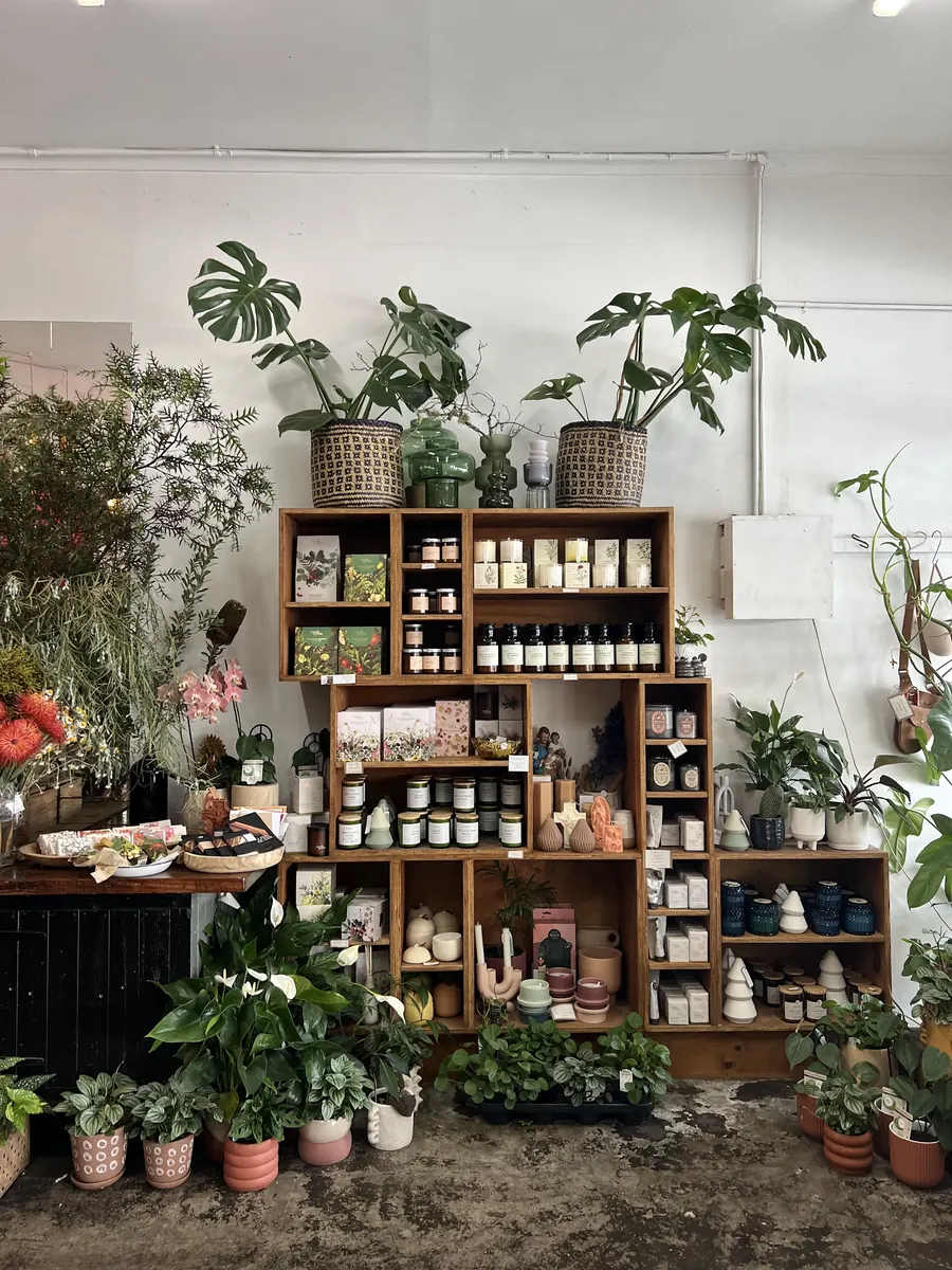 Timber shelves of candles, soaps and gifts surrounded by potted plants