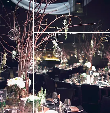 Event styling with bare branches and hanging glass orbs over candlelit tables
